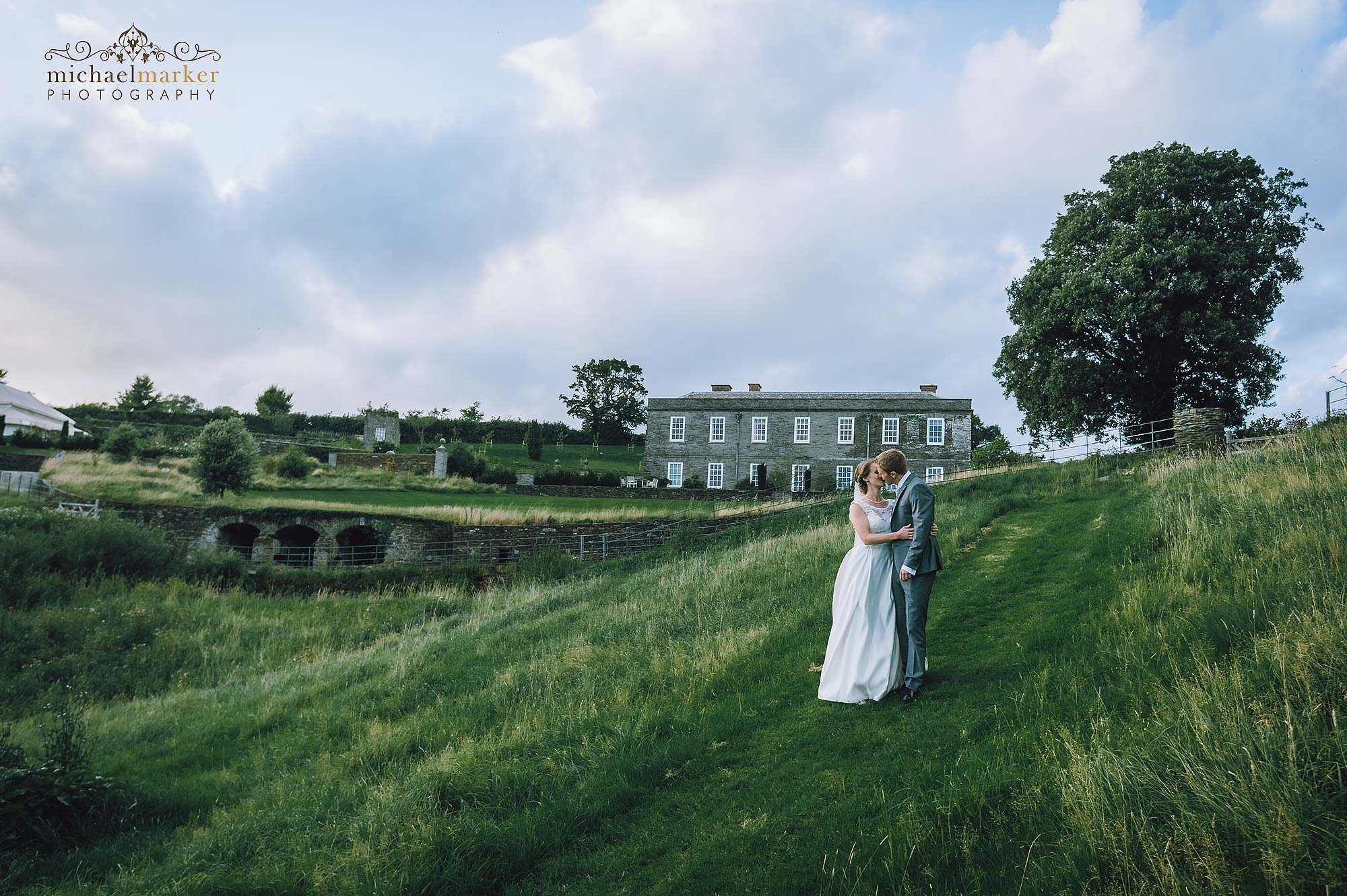 Bride and groom kiss in the fields in front of Shilstone House in Devon.