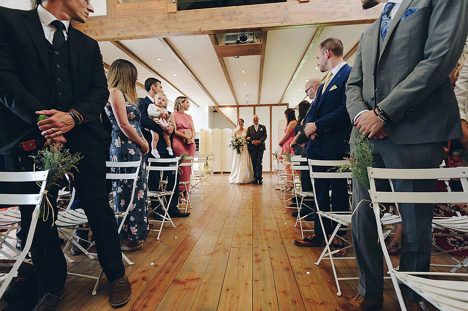 Bride and father walk arm in arm down the aisle at Shilstone House wedding venue