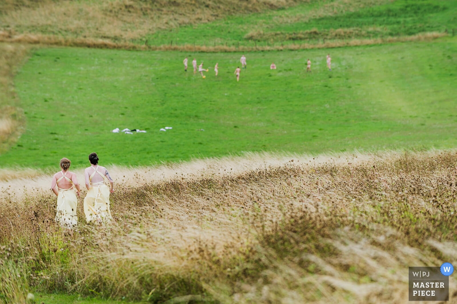 Bridesmaids running to steal groomamans colthes whilst they play football at a wedding