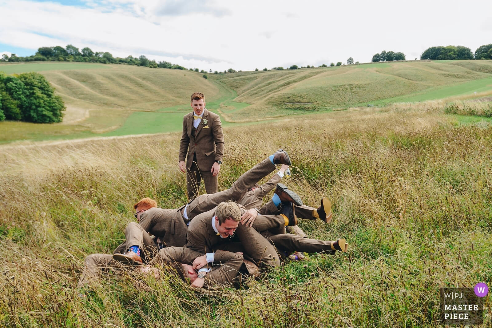 Groomsmen pile on top of each other at Wiltshire wedding. award winning photograph from WPJA