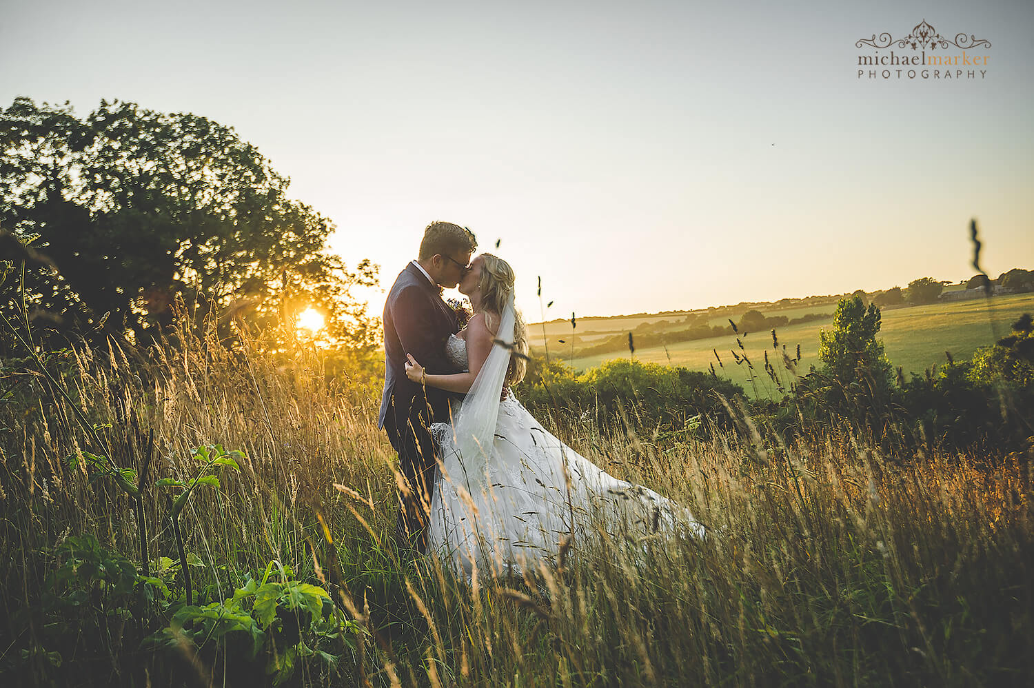 Bride and groom kiss at sunset in field at Trevenna Barns